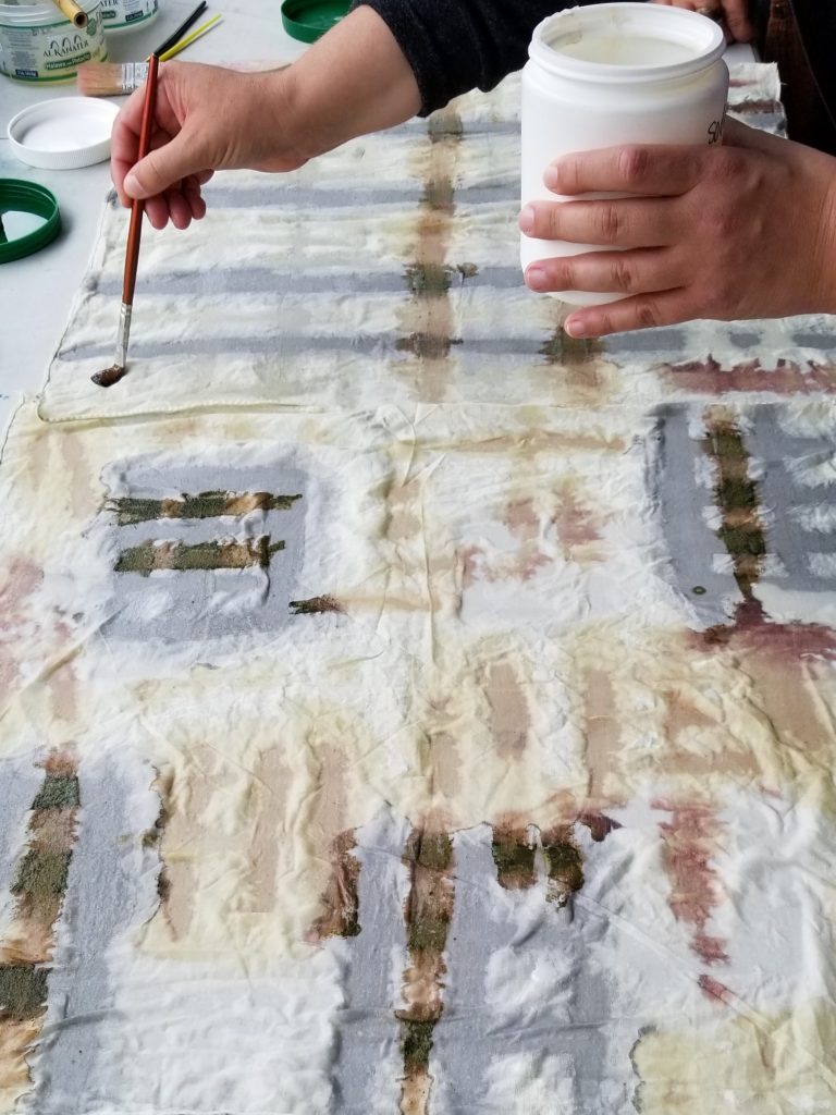 Hands painting a design onto fabric.